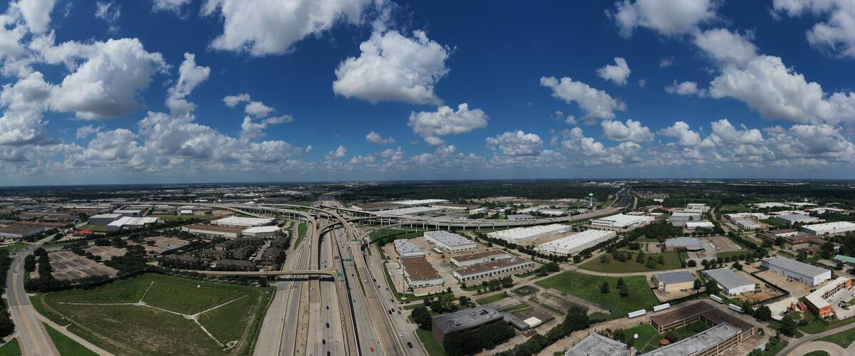 An aerial view of a large industrial area with multiple buildings, roads, and a highway interchange.