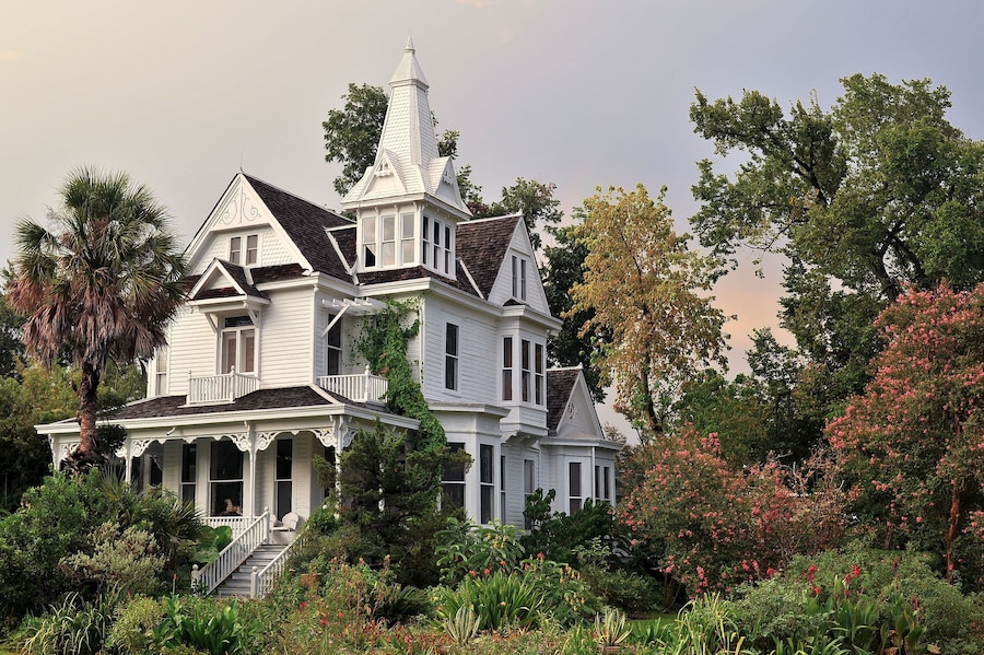 Charming Victorian-style home surrounded by lush gardens in Houston Heights, a historic neighborhood known for its character.