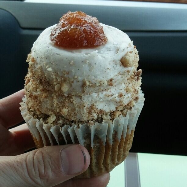 Apple pie cupcake underneath a mountain of frosting, cinnamon crumbles and a dollop of apple pie filling.