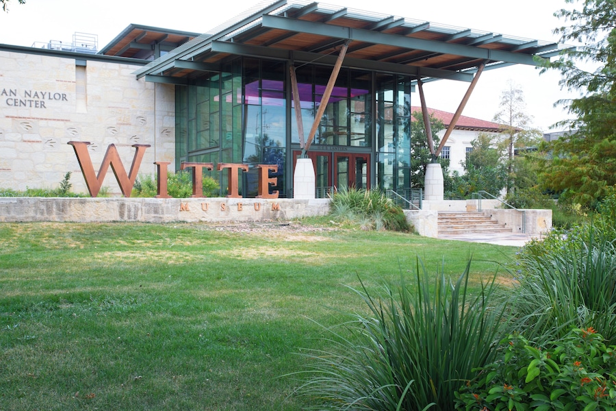 A building with large letters spelling "Witte Museum" and a stone wall with "An Naylor Center" text.