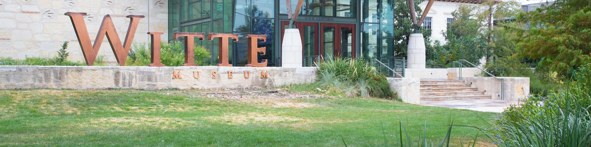 Um edifício com letras grandes formando a palavra "Witte Museum" e uma parede de pedra com o texto "An Naylor Center".