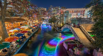 Christmas Lights illuminated San Antonio downtown River Walk with Restaurants on side and boats on the river in Texas, USA