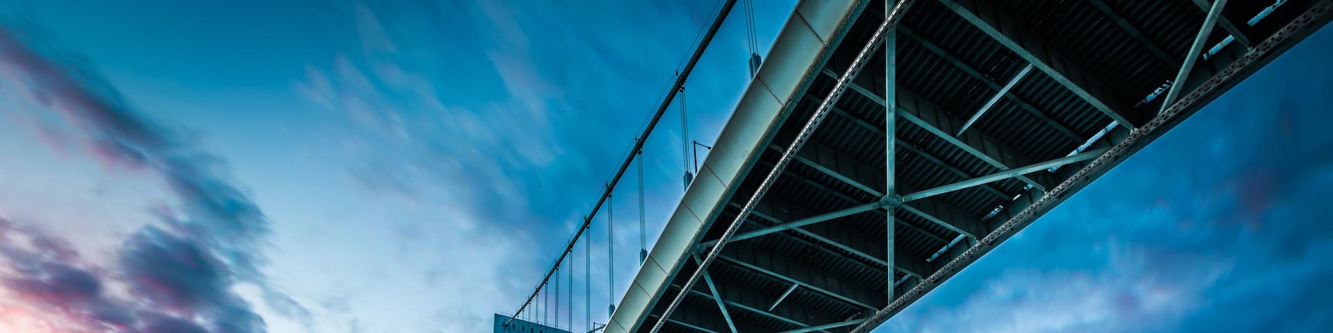 A large suspension bridge with a clear sky and a sunset.