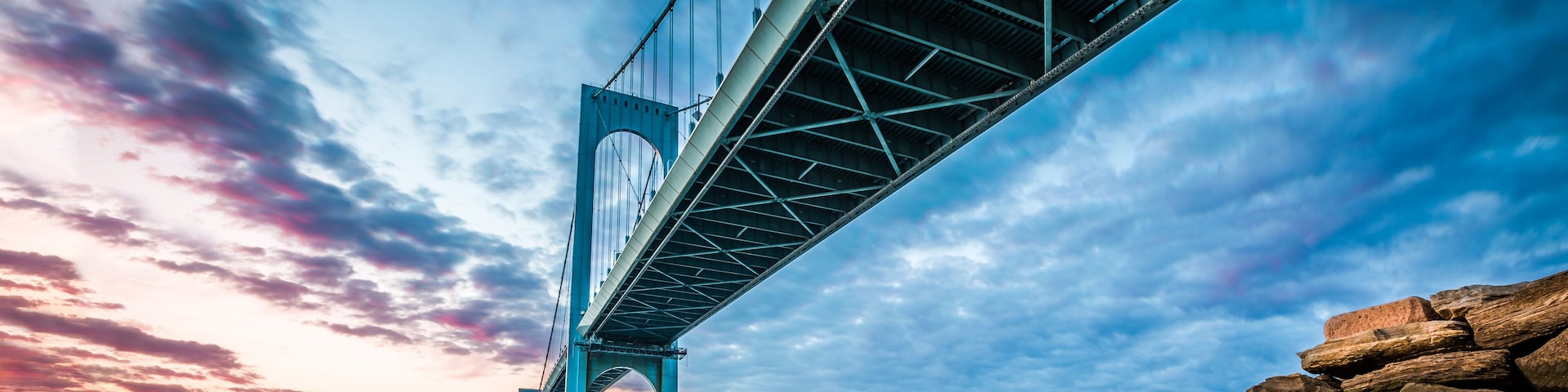 Un grand pont suspendu, avec un ciel dégagé et un coucher de soleil.
