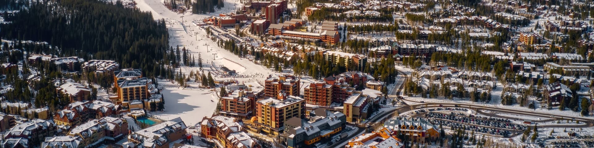 A snow-covered mountain town with ski slopes, buildings, and a road network.