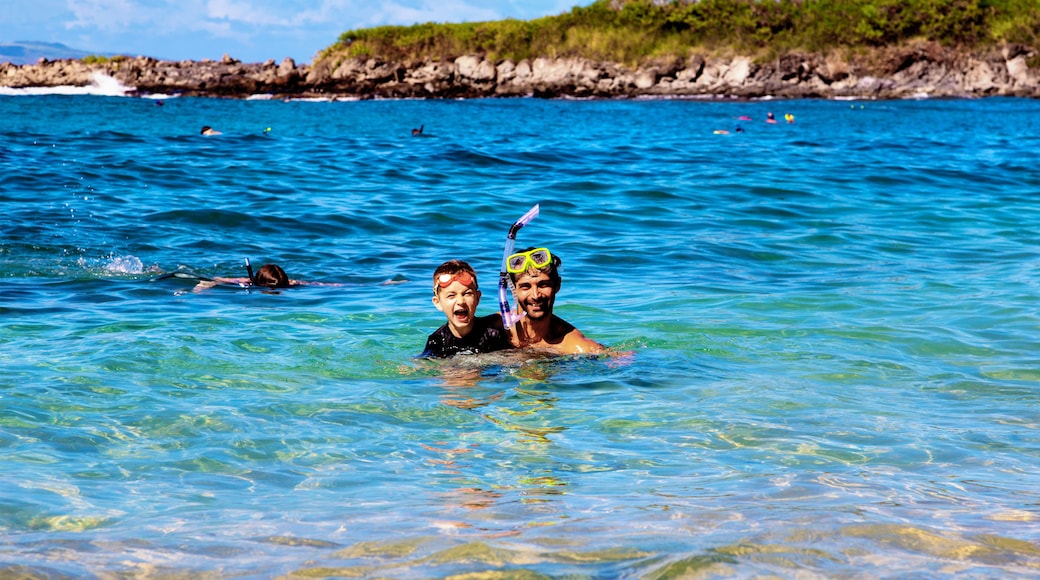 A father and son in the ocean water at Kapalua Bay with snorkeling gear and posing for the camera; Maui, Hawaii, United States of America