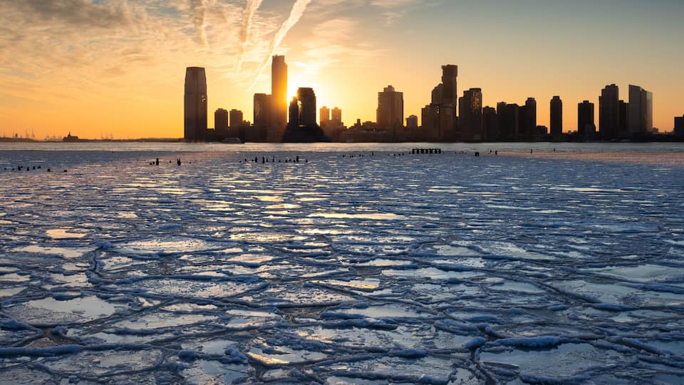 Sunset on the frozen Hudson River with skyline view of Downtown Jersey City skyscrapers (Exchange Place and Newport). New Jersey