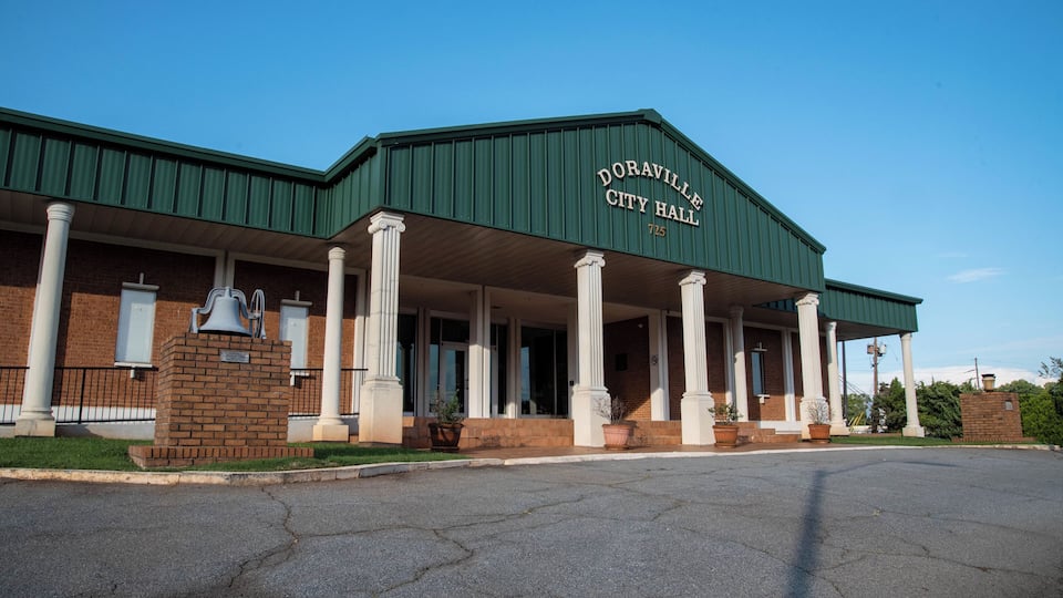 Doraville City Hall with a green roof, white columns, and a brick facade.