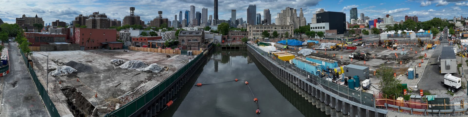 A cityscape with a river, construction sites, and a mix of modern and historic buildings.