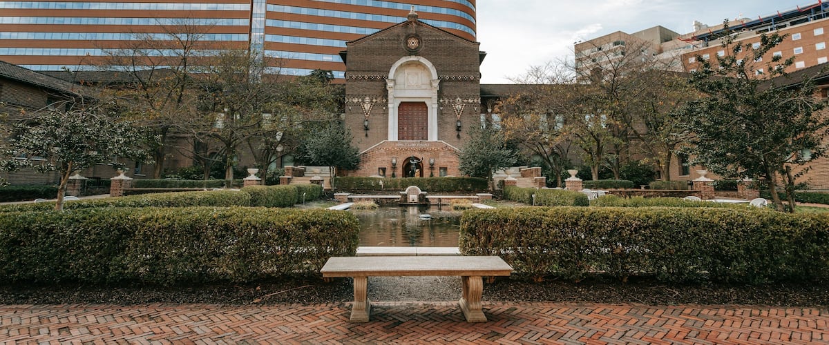 A courtyard with a fountain, a bench, and a building with a Penn logo.