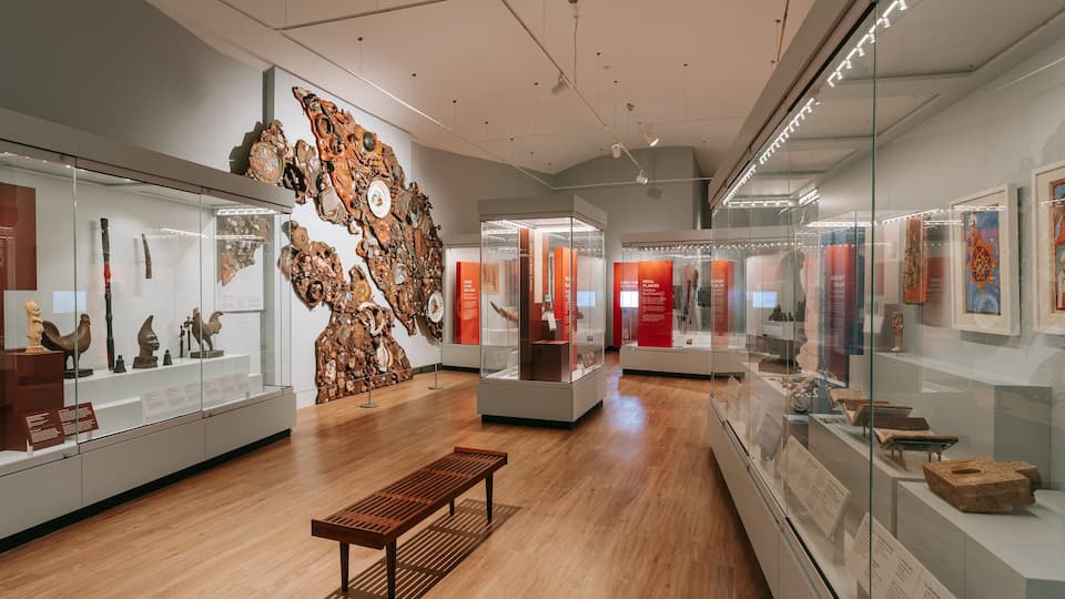 An art museum with wooden floors, glass display cases, and various sculptures.