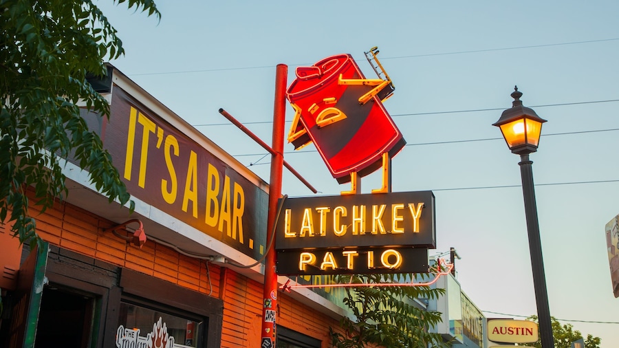 Un bar appelé « It’s a Bar », avec une enseigne au néon indiquant « Latchkey Patio » et un lampadaire.