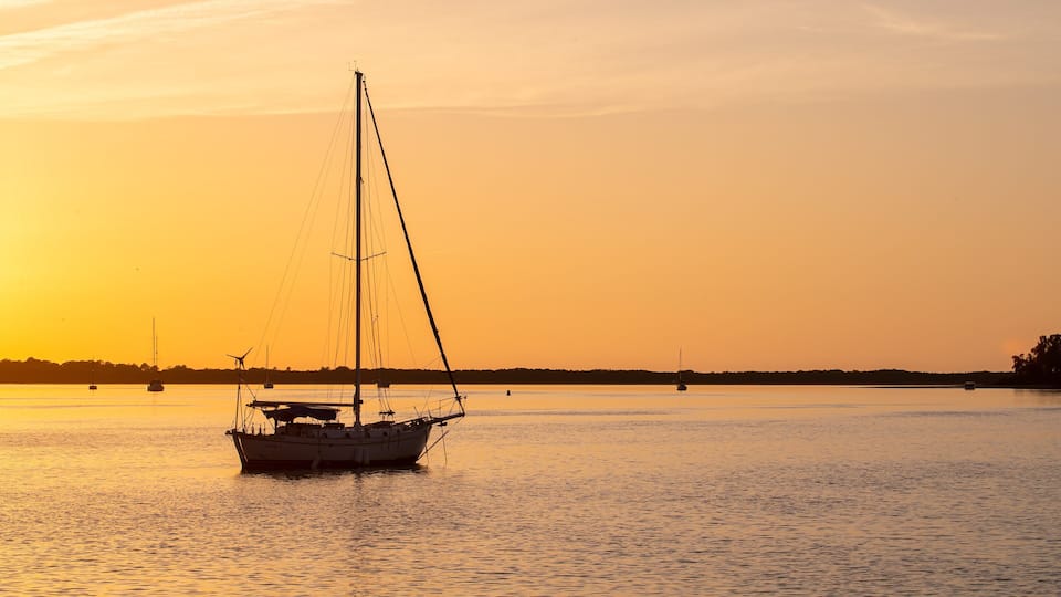 A sailboat on calm water during sunset.