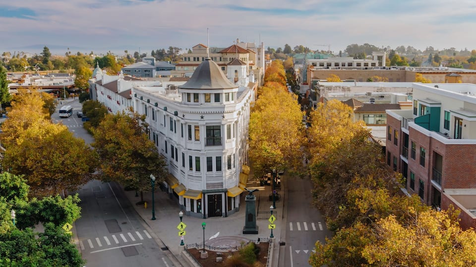 Downtown, Santa Cruz, California, USA, during autumn. The image shows the street with trees in fall colors, buildings, and a bus. The photo shows the city's architecture.
