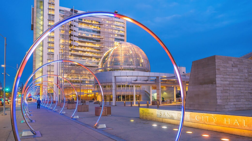 A modern building with a dome and a curved light installation in front.