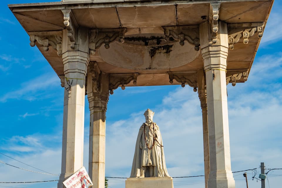 Een historisch monument met een koepel en standbeeld, omringd door kleurrijke muurschilderingen.