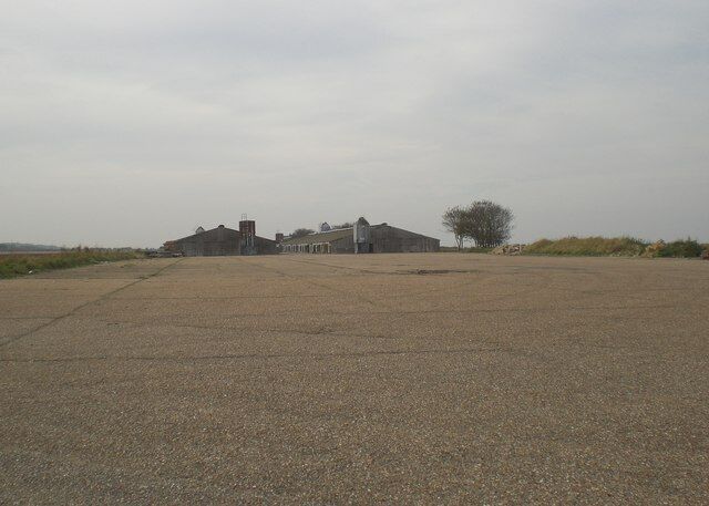 View along runway of former RAF Langham Bernard Matthews bought the airfield in the 1960's and built turkey sheds straight on top of the concrete runways and, in the process, preserved large sections of them. Nowadays the sheds are run by another poultry producer. This photograph was taken at the intersection of two of the runways. See http://www.rafbnmp.org.uk/langham.htm for a history of the base.