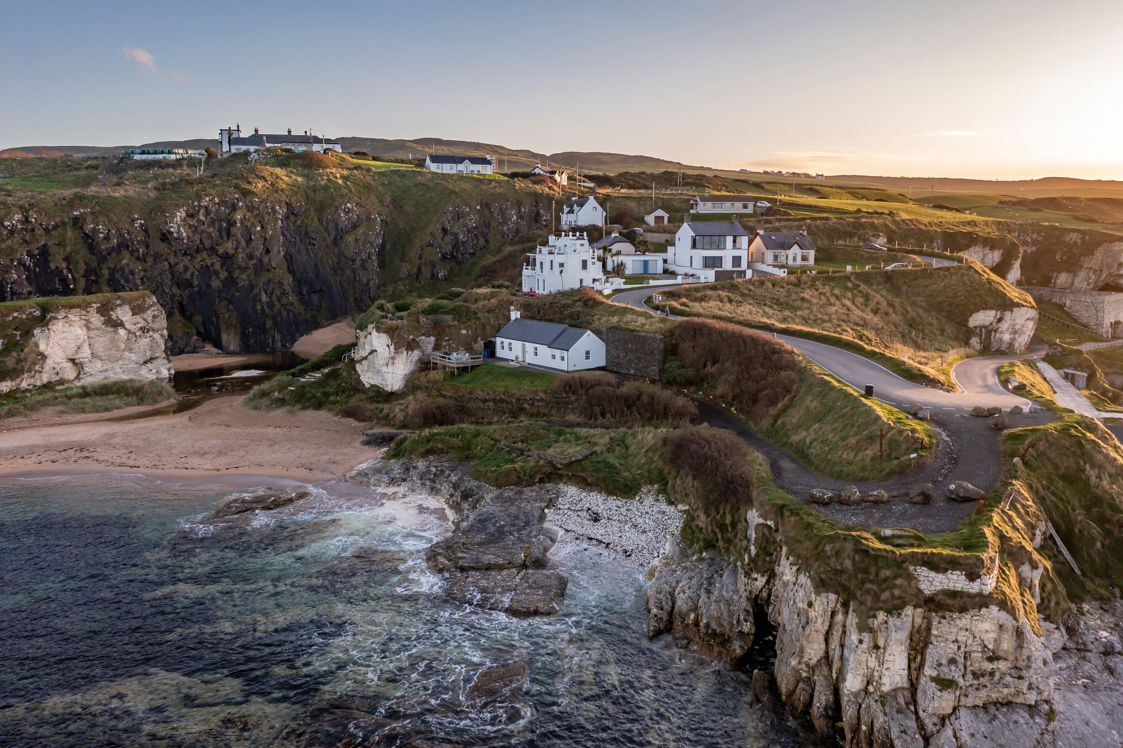 A coastal village with white houses, cliffs, and a beach.