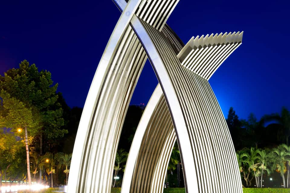 A modern architectural structure with curved, ribbed design elements, set against a night sky.