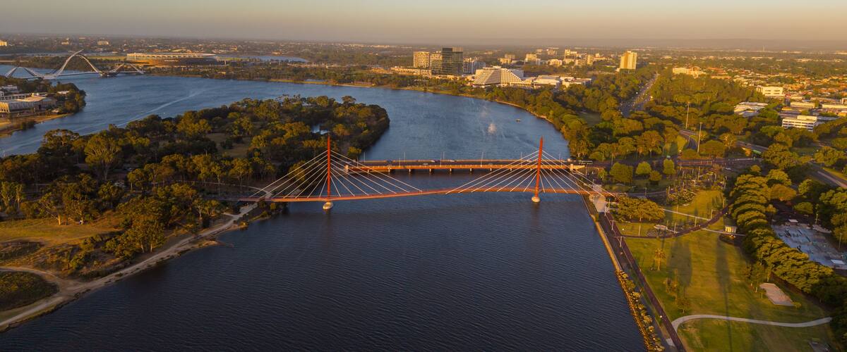 Aerial view of Perth city skyline with Boorloo bridge lit up connecting Heirisson island with walking and cycling path along the Swan river