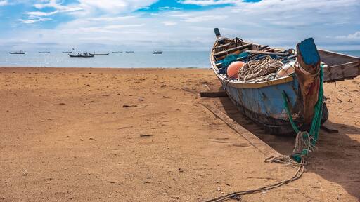 Fishing boat missions on the beach waiting for the next fishing trip. This boat is located on the tropical shore of Keta Ghana West Africa 2021