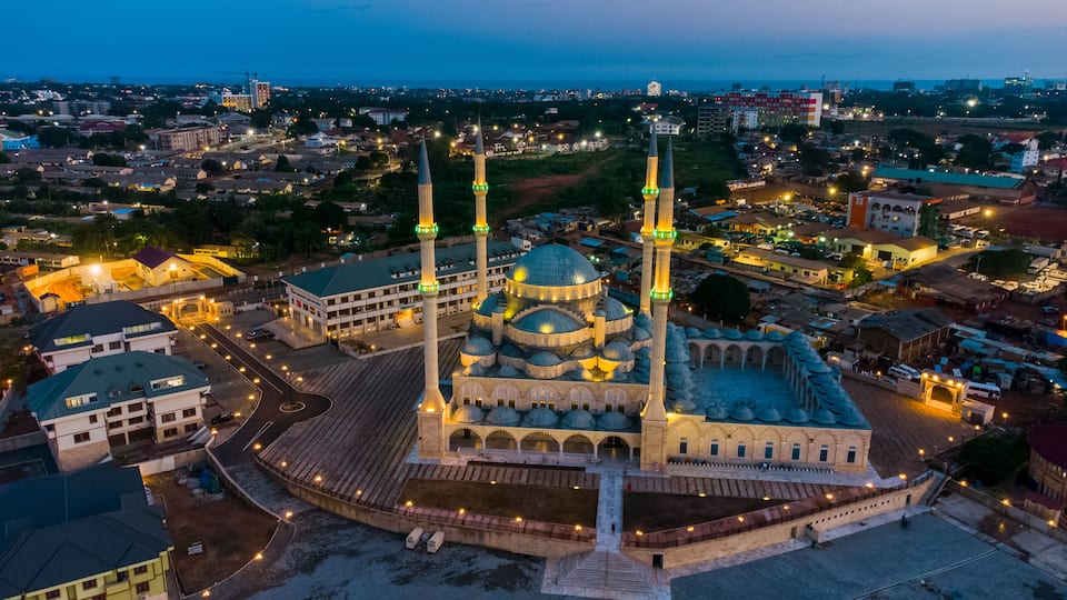 A mosque with two minarets, a large central dome, and a courtyard.