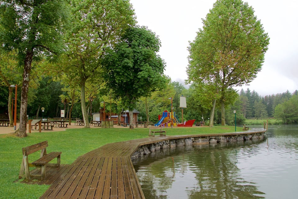 A park with a wooden boardwalk, picnic tables, a playground, and a lake.