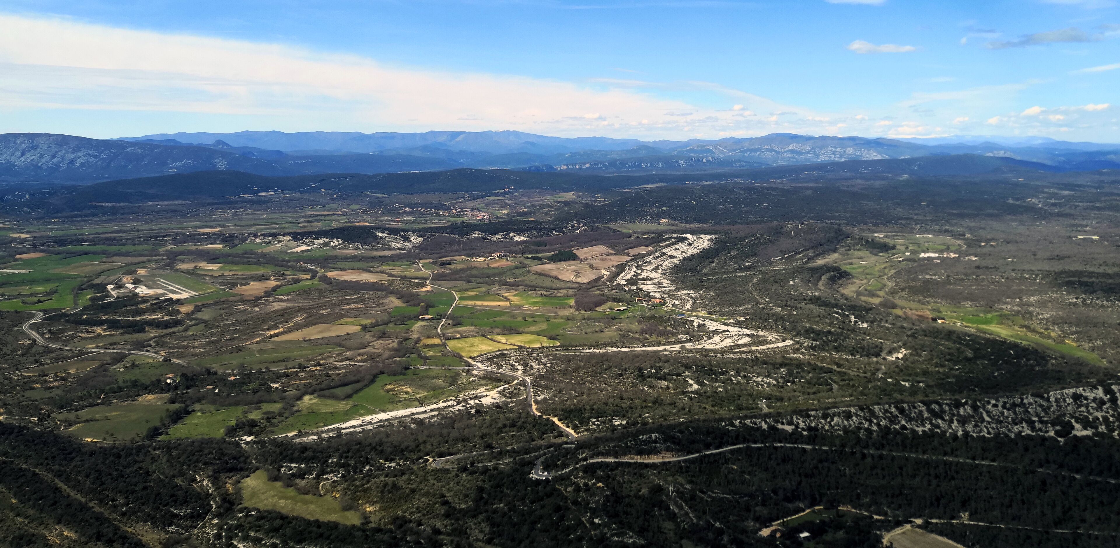 A mountainous landscape with winding roads and patches of greenery.