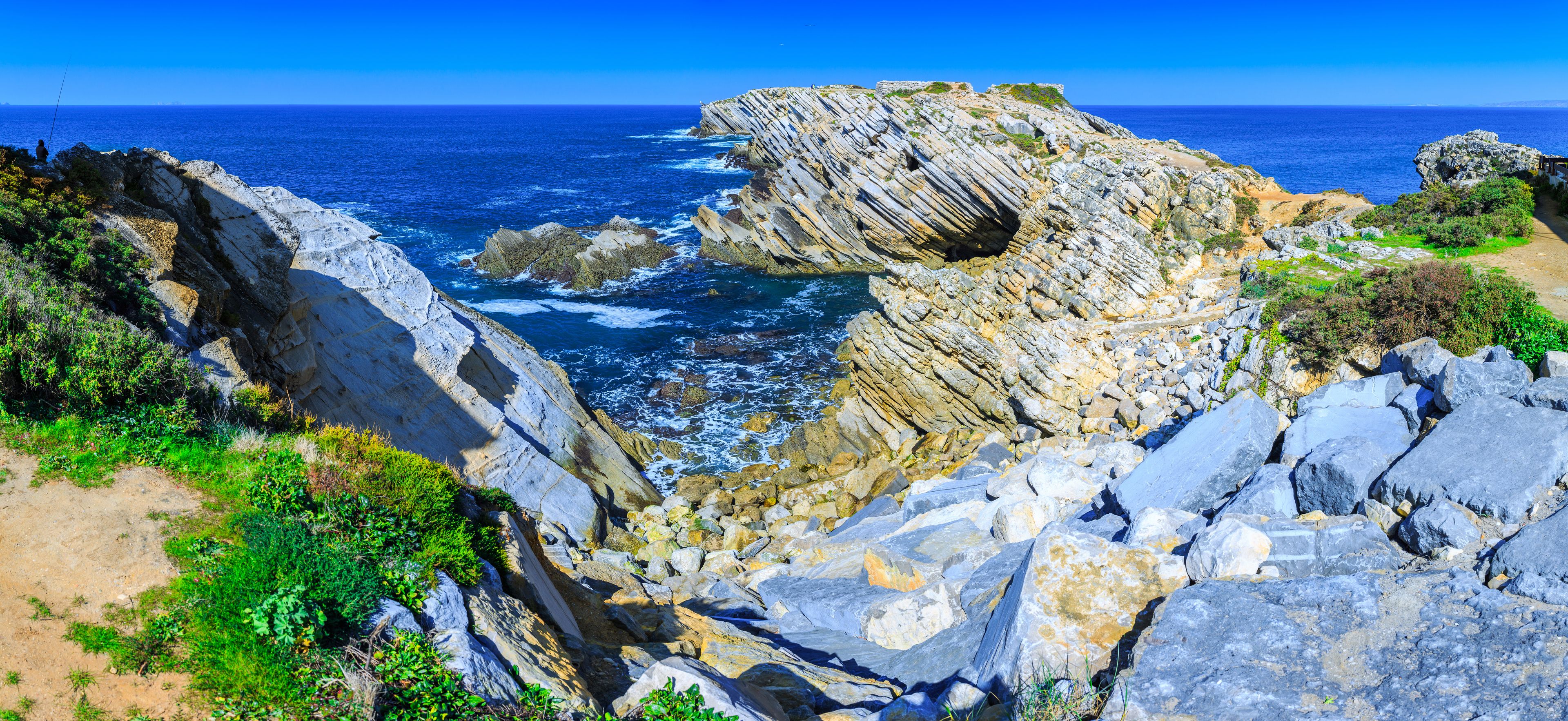 A rocky coastline with a prominent rock formation and the ocean in the background.