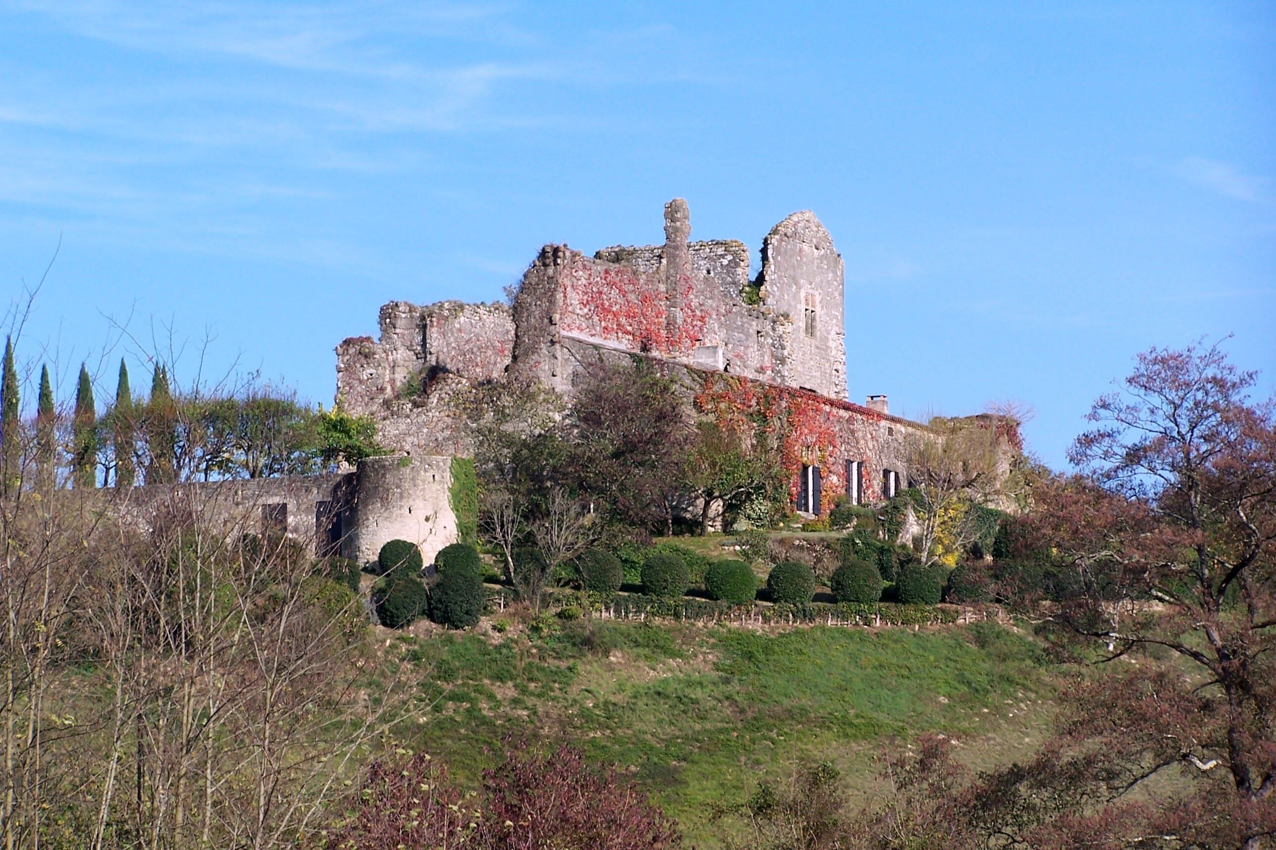 An ancient castle with ivy-covered walls, a turret, and a well-maintained garden.