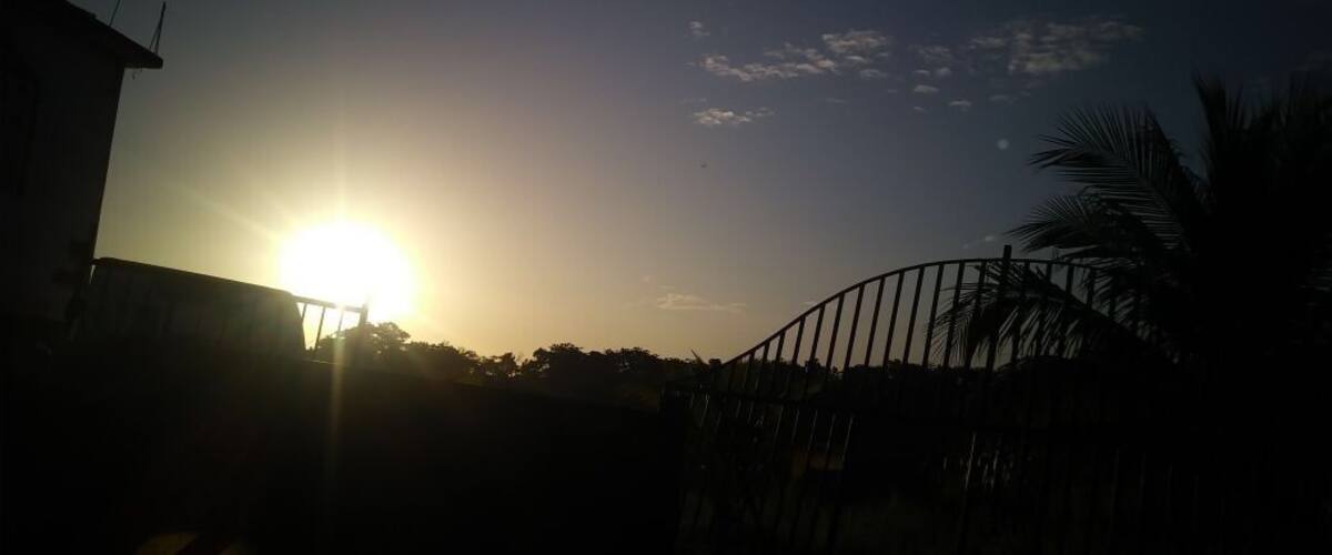A sunset over a residential area with a house and a metal gate.