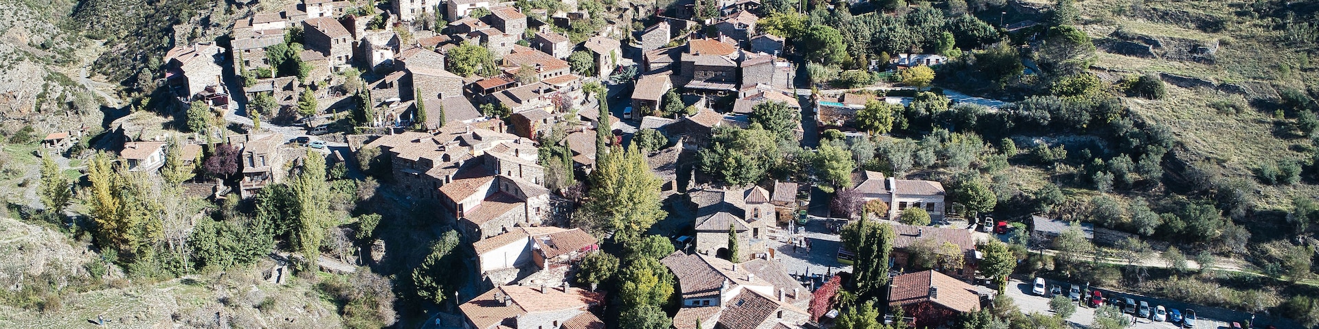 Vila montanhosa com casas em terraços e uma estrada sinuosa.