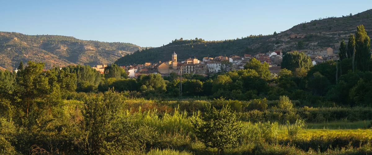 Panoramic view of a village in the middle of the countryside illuminated by the last rays of the sunset. Casas Altas in Rincón de Ademuz, Spain, summer 2023