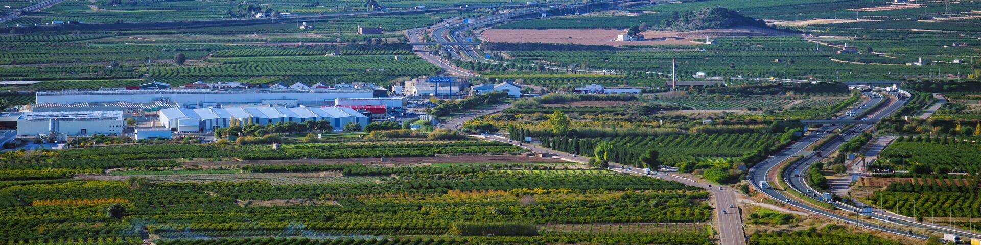 A cityscape with a prominent hill, agricultural fields, and industrial buildings.