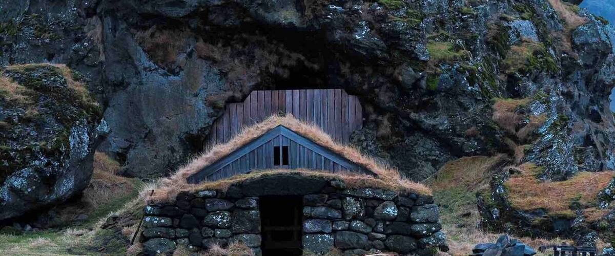 A stone house with a thatched roof nestled in a rocky landscape.