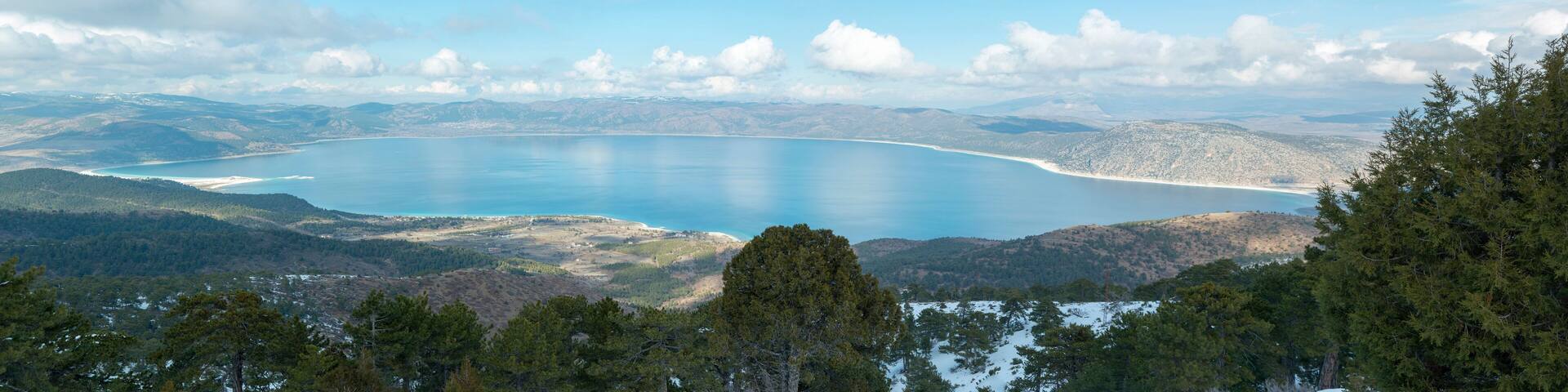 Un paisaje costero con una extensa masa de agua, rodeado de colinas y bosques densos.