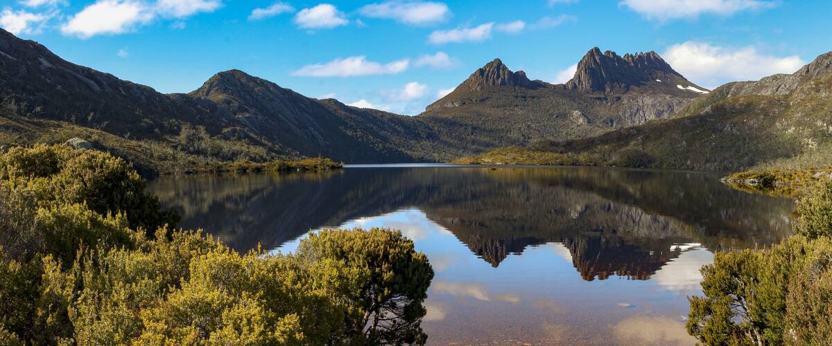 A mountain lake with reflections of the peaks and surrounding trees.