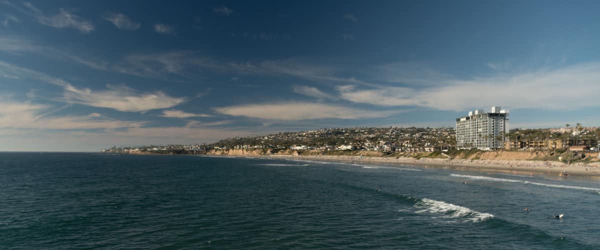 A coastal cityscape with a beach, ocean, and a dense residential area with a prominent hotel.