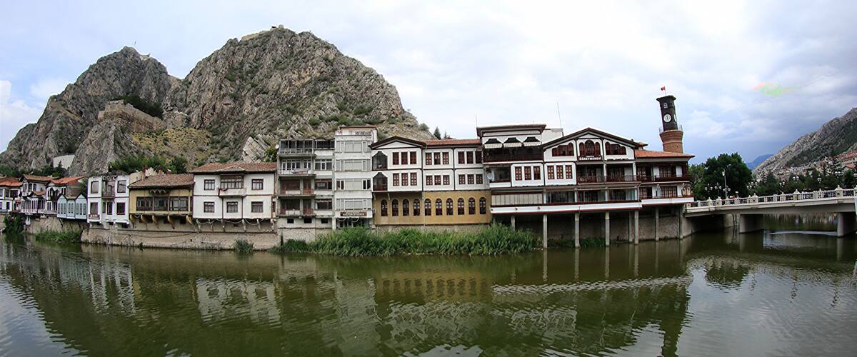 A riverside town with historic buildings, a bridge, and mountains in the background.