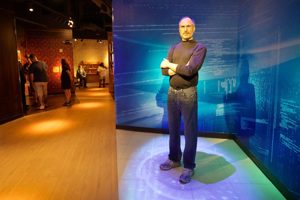 A person standing in a museum hallway with a large digital display in the background.