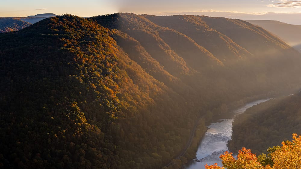 A river winding through a mountainous landscape with dense forests and autumn foliage.