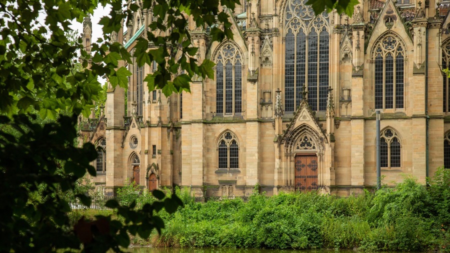 Ein historisches Gebäude mit gotischer Architektur, großen Bogenfenstern und aufwendiger Steinmetarbeit.