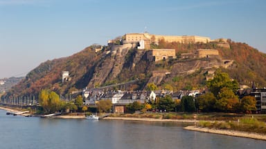 Um castelo numa colina com vista para um rio.