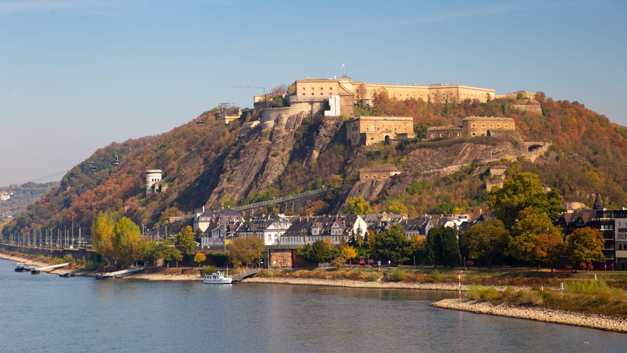Un château perché sur une colline, dominant une rivière.