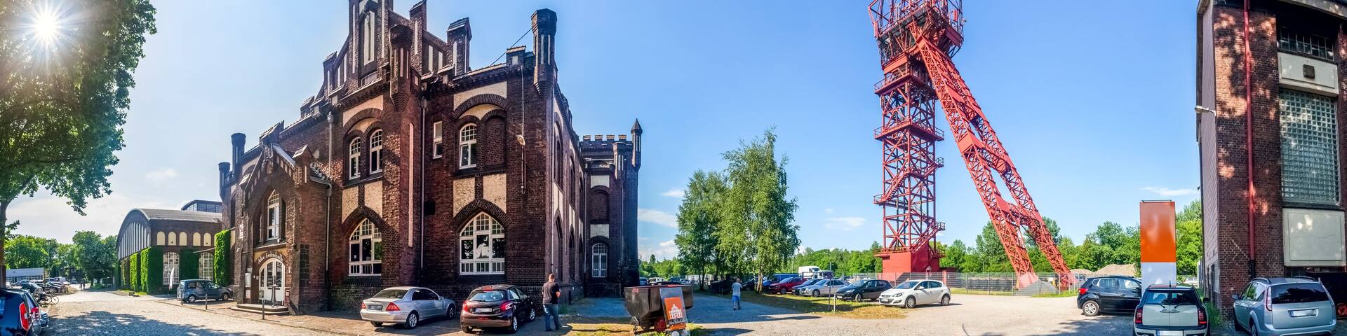 A historic building with arched windows and a red crane structure.