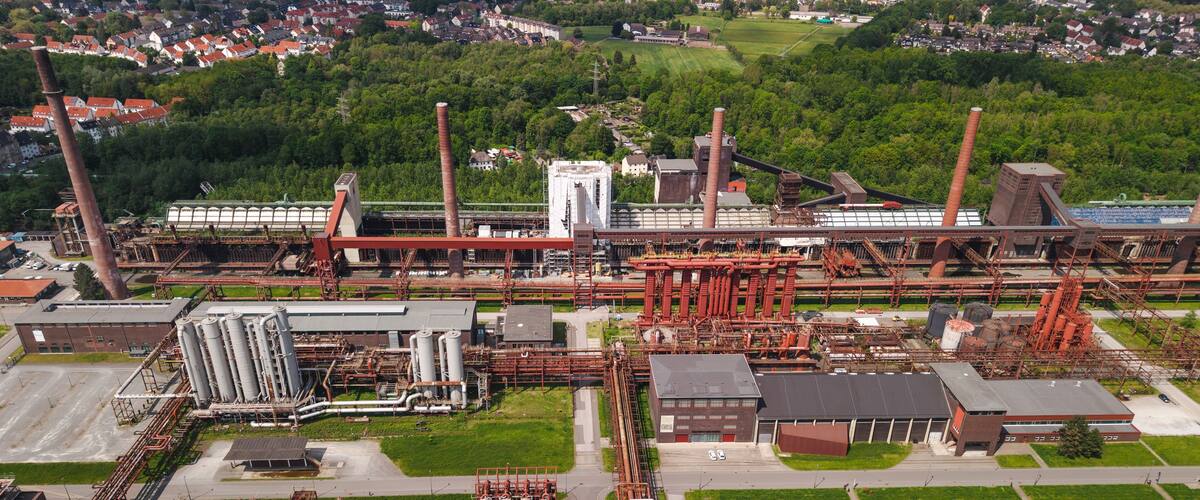 Ein Industrieareal mit mehreren hohen Schloten, Lagertanks und umfangreichen Rohrleitungen.