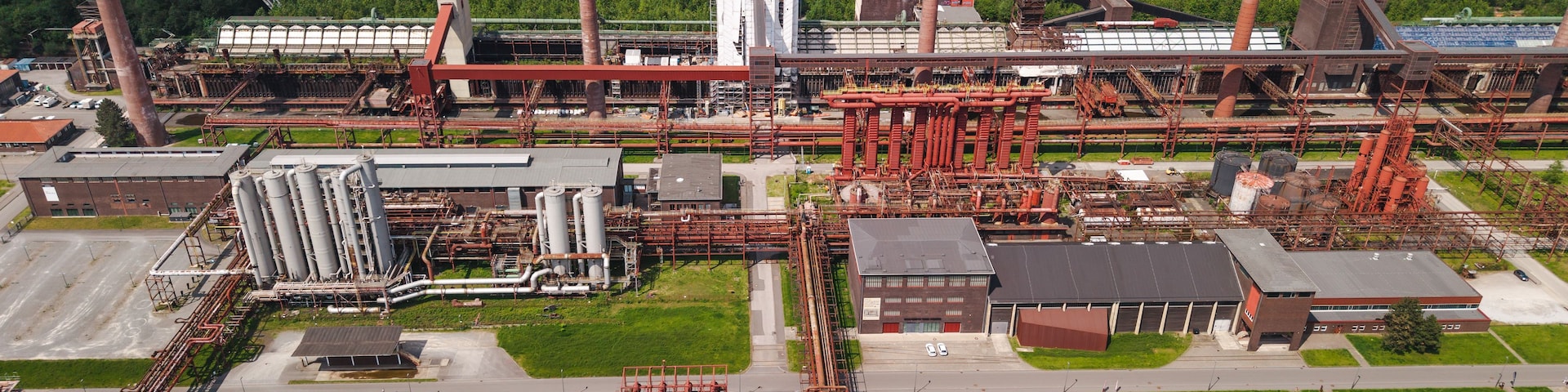 Ein Industrieareal mit mehreren hohen Schloten, Lagertanks und umfangreichen Rohrleitungen.