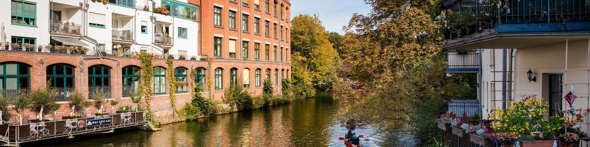 Un canal flanqueado por edificios, una embarcación con gente y follaje otoñal.