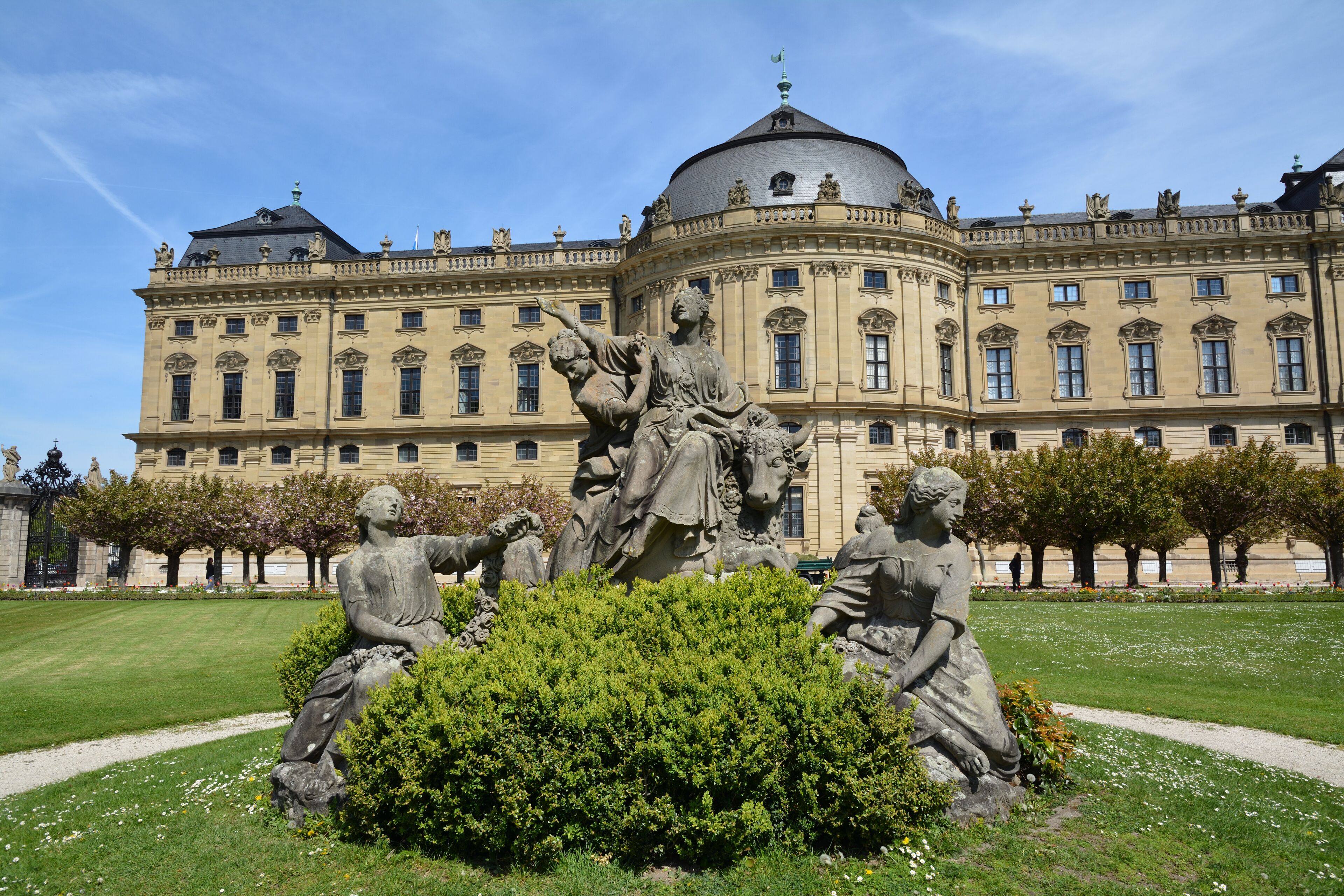 A classical statue garden in front of a large, ornate building with a dome.
