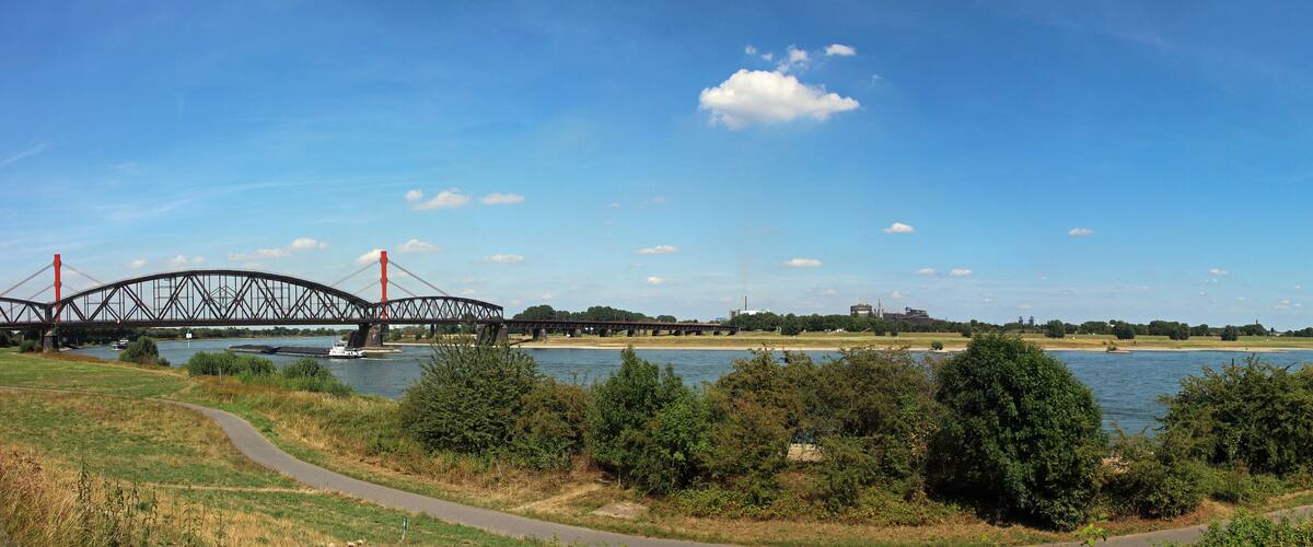 Ein Fluss mit einer Brücke, einem Boot und einem Weg entlang des Ufers.